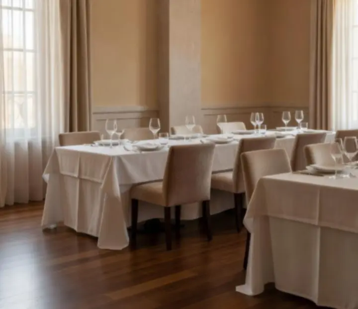 Salón privado elegante de restaurante con luz natural y mesa preparada para cena.